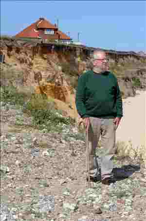 Peter Boggis standing below the eroded cliffs